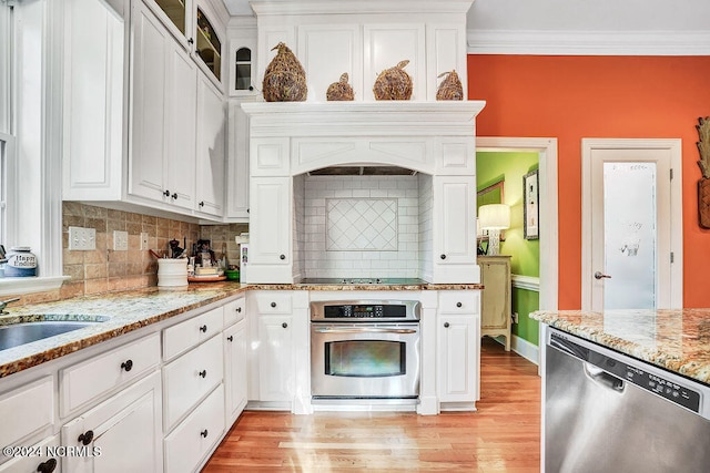 kitchen featuring stainless steel appliances, white cabinets, ornamental molding, light stone countertops, and light hardwood / wood-style flooring