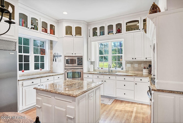 kitchen with white cabinets, built in appliances, sink, and a center island