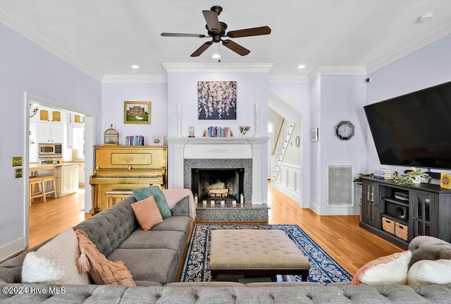 living room featuring ornamental molding, light hardwood / wood-style floors, and ceiling fan