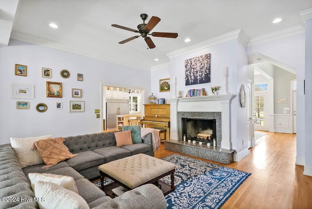 living room with a premium fireplace, hardwood / wood-style flooring, crown molding, and ceiling fan