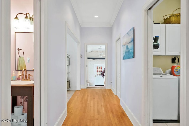 hallway with sink, light wood-type flooring, and ornamental molding