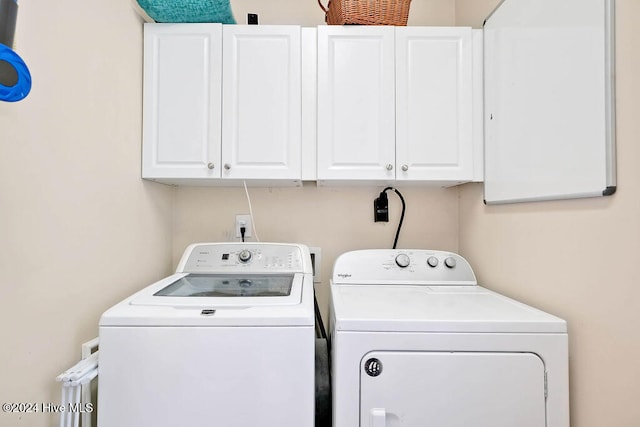 clothes washing area featuring cabinets and washer and dryer