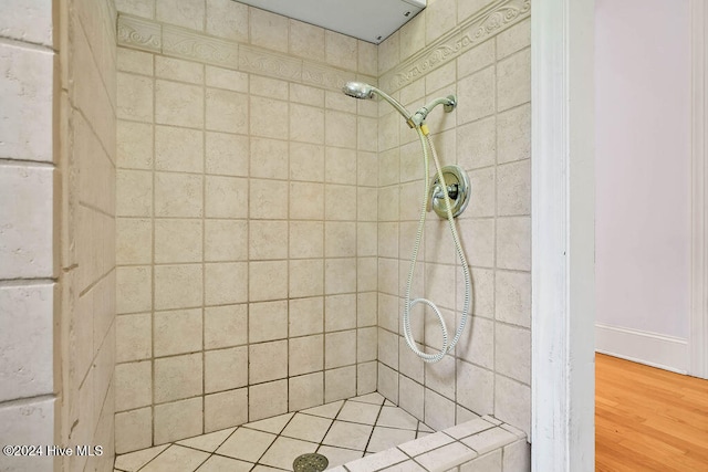 bathroom with wood-type flooring and tiled shower