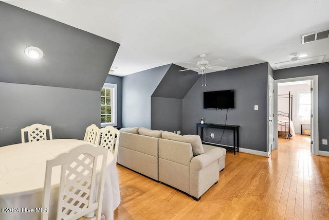 living room with ceiling fan, light wood-type flooring, and vaulted ceiling