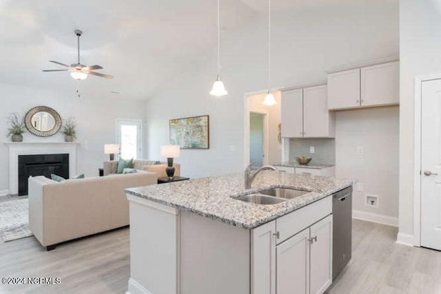 kitchen featuring sink, an island with sink, white cabinetry, light hardwood / wood-style floors, and light stone counters