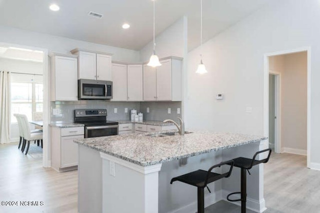 kitchen featuring light hardwood / wood-style floors, white cabinetry, stainless steel appliances, and decorative light fixtures