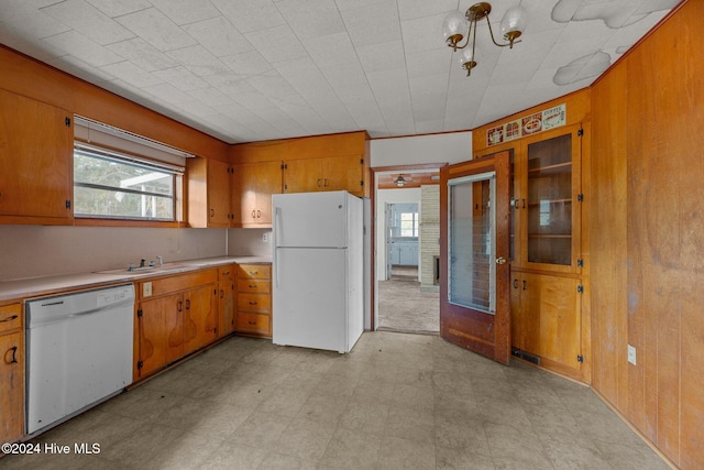 kitchen featuring white appliances, wooden walls, and sink