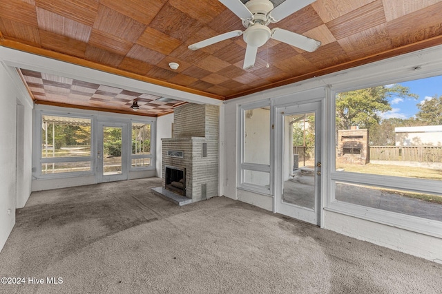 unfurnished living room with ceiling fan, carpet flooring, wooden ceiling, and a fireplace