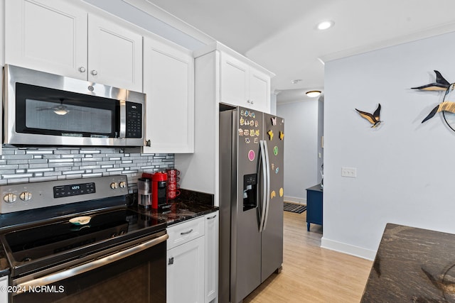 kitchen with decorative backsplash, white cabinets, light wood-type flooring, dark stone counters, and stainless steel appliances