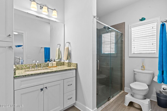 bathroom featuring vanity, hardwood / wood-style flooring, toilet, and an enclosed shower