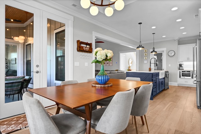 dining area featuring sink, ornamental molding, and light hardwood / wood-style flooring