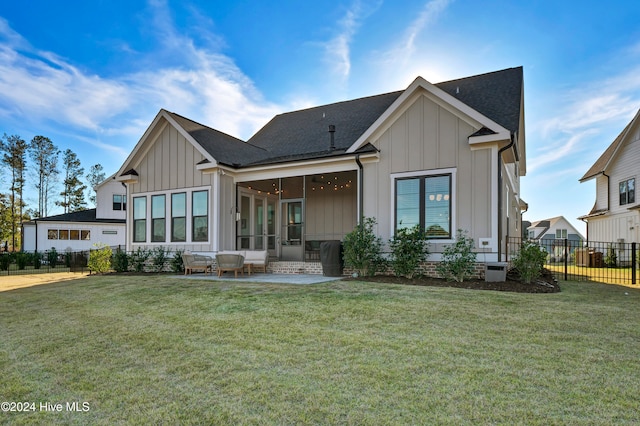 back of house featuring a patio area, a sunroom, and a lawn