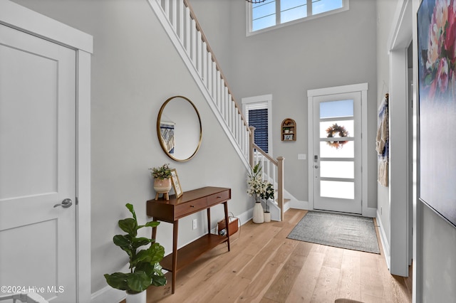 entryway with a high ceiling, a wealth of natural light, and light hardwood / wood-style flooring