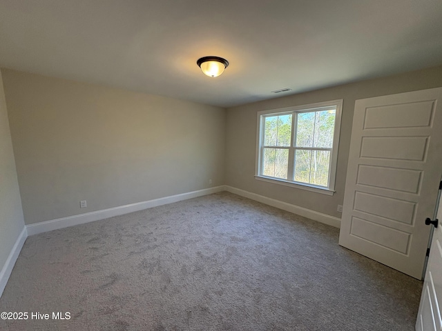 carpeted spare room featuring visible vents and baseboards