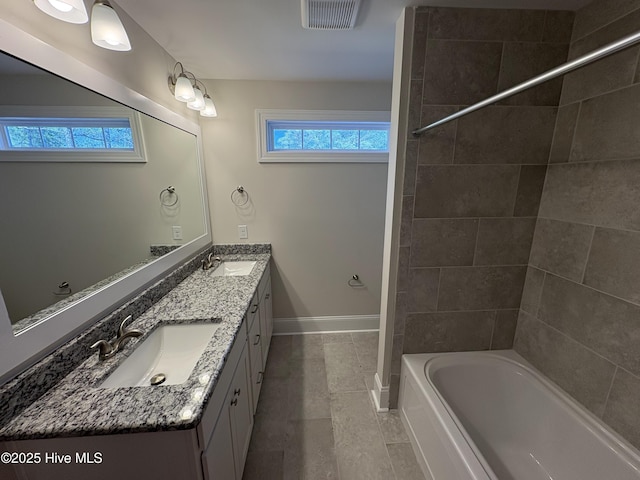 bathroom with double vanity, baseboards, visible vents, and a sink