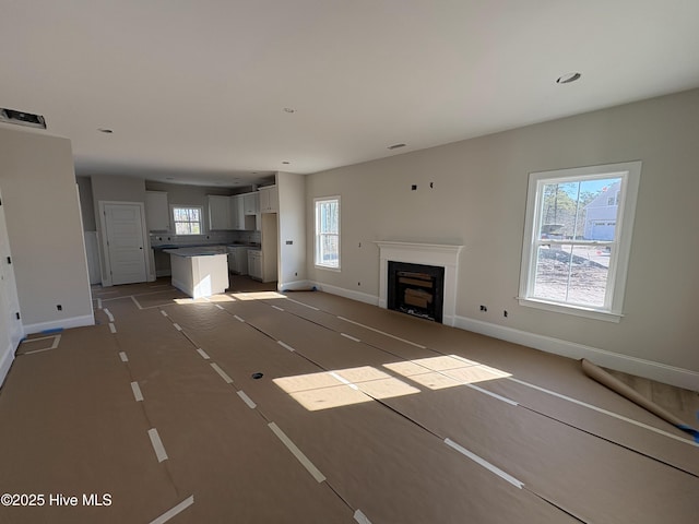 unfurnished living room featuring recessed lighting, a fireplace, and baseboards