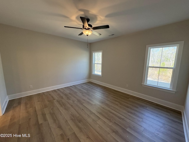 spare room featuring dark wood-style flooring, visible vents, ceiling fan, and baseboards