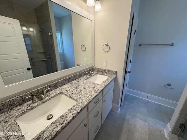 bathroom featuring a stall shower, a sink, toilet, and baseboards