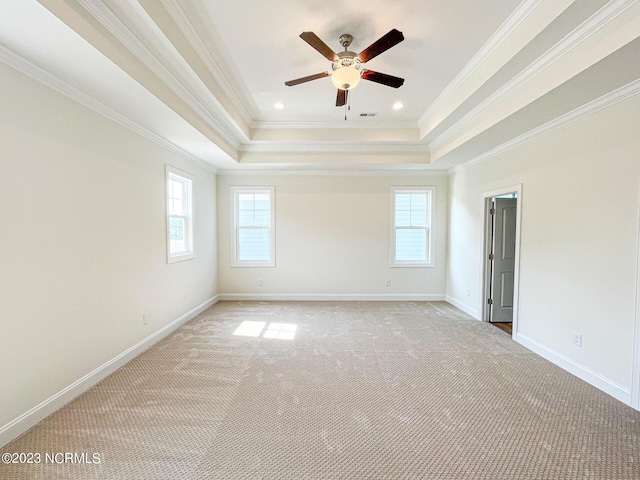 carpeted spare room featuring a raised ceiling, crown molding, and ceiling fan