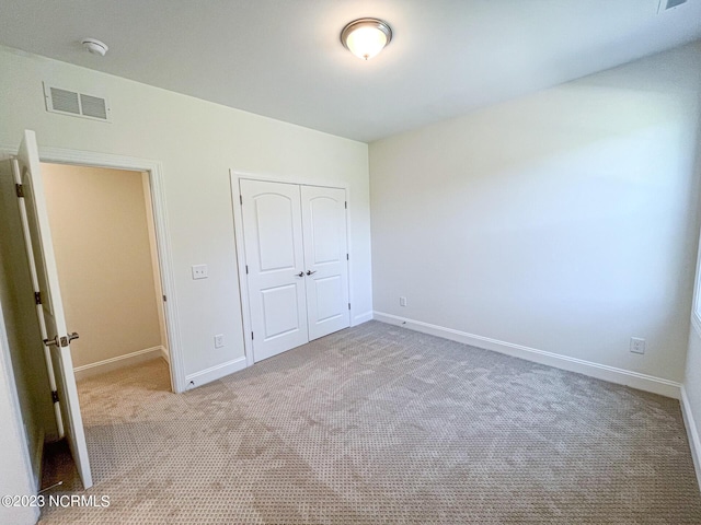 unfurnished bedroom with light carpet and a closet