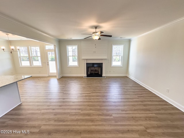 unfurnished living room with dark hardwood / wood-style floors, crown molding, ceiling fan with notable chandelier, and a wealth of natural light