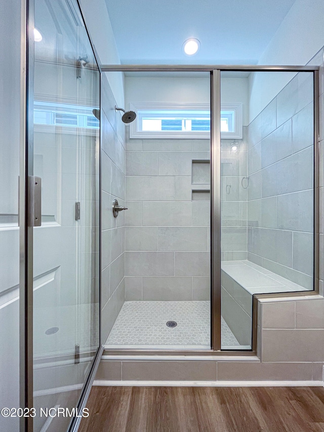 bathroom with a shower with shower door and hardwood / wood-style floors