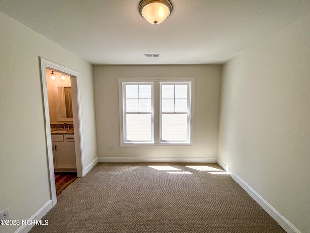 unfurnished bedroom featuring connected bathroom, carpet floors, and sink