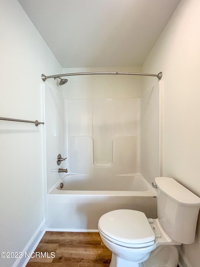 bathroom featuring toilet, hardwood / wood-style flooring, and tub / shower combination