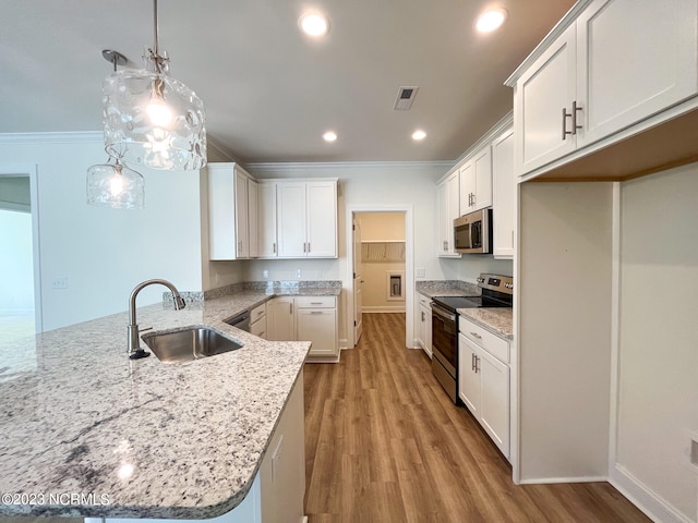 kitchen with white cabinets, hanging light fixtures, appliances with stainless steel finishes, light hardwood / wood-style floors, and sink