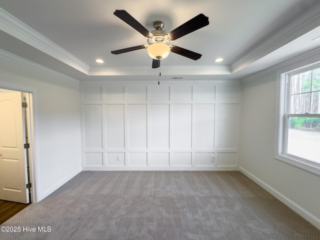 carpeted empty room featuring a raised ceiling, ceiling fan, and ornamental molding