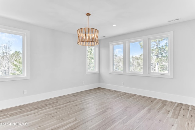 empty room featuring a chandelier and light hardwood / wood-style floors