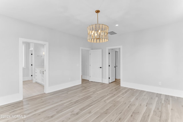 unfurnished room with light hardwood / wood-style floors and a notable chandelier