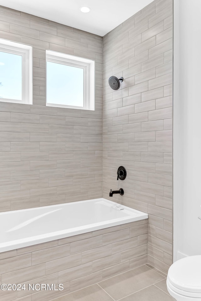 bathroom featuring toilet, tiled shower / bath combo, and tile patterned flooring