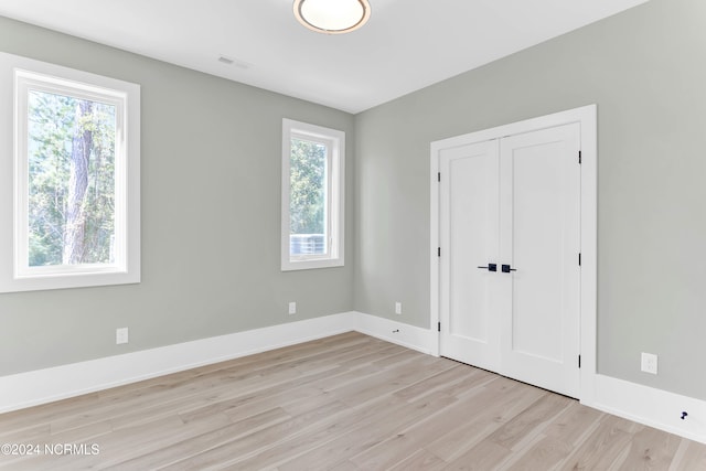 unfurnished bedroom with multiple windows and light wood-type flooring