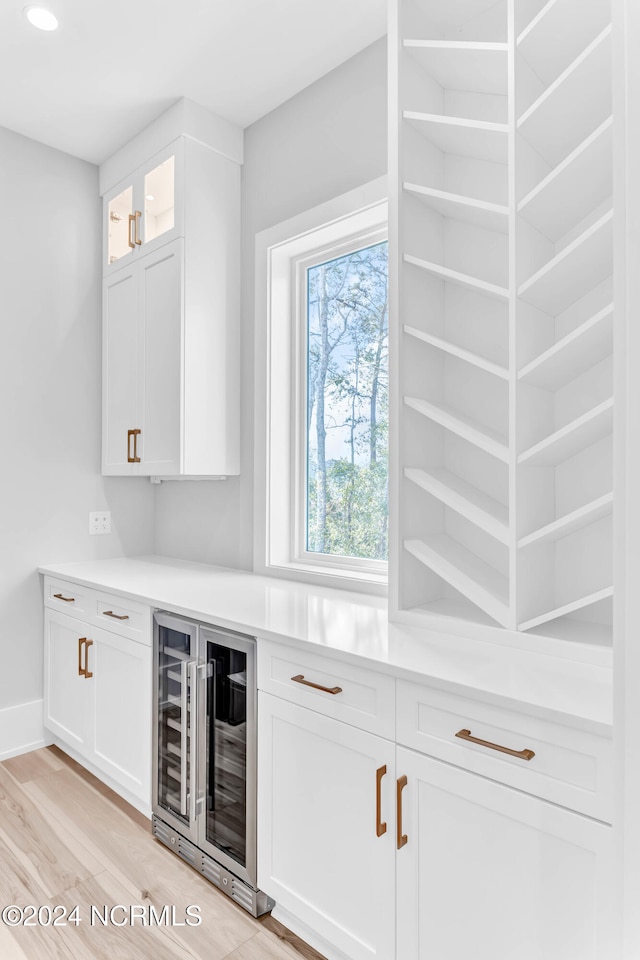 bar featuring wine cooler, white cabinets, and light wood-type flooring