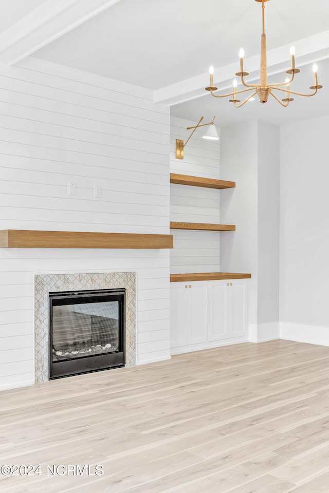 unfurnished living room with beamed ceiling, wooden walls, a fireplace, and light wood-type flooring