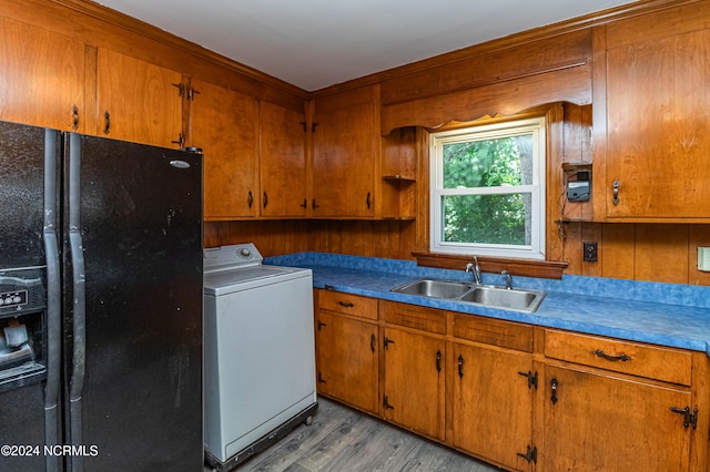 kitchen with light hardwood / wood-style flooring, black refrigerator with ice dispenser, washer / clothes dryer, and sink