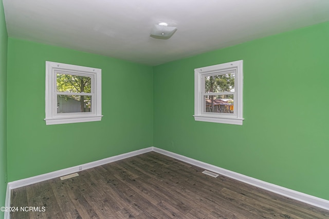 unfurnished room featuring dark wood-type flooring and a healthy amount of sunlight