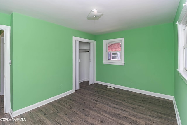 unfurnished bedroom with a closet and dark wood-type flooring