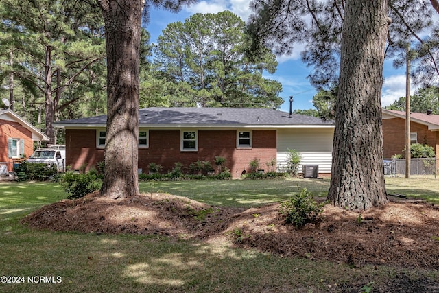 rear view of property with cooling unit and a lawn