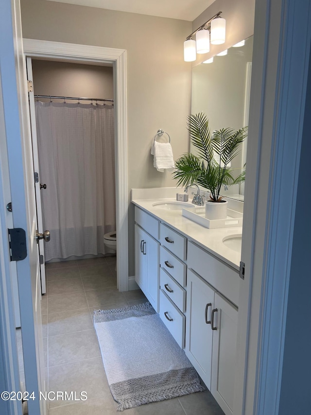 full bathroom with toilet, tile patterned flooring, double vanity, and a sink