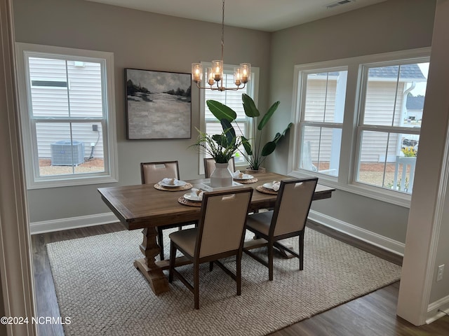 dining area featuring dark wood-type flooring, an inviting chandelier, visible vents, and baseboards