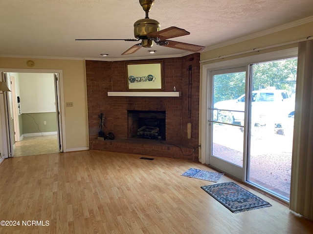 unfurnished living room with crown molding, a brick fireplace, light hardwood / wood-style flooring, ceiling fan, and a textured ceiling