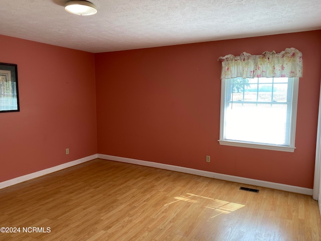 empty room featuring wood-type flooring and a textured ceiling