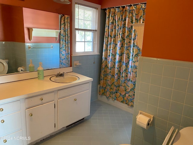 bathroom featuring tile patterned flooring, vanity, toilet, and tile walls