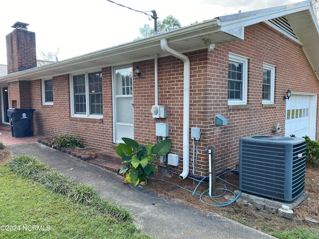 view of side of home with a garage and central air condition unit