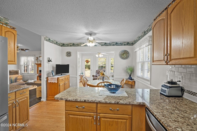 kitchen with decorative backsplash, light hardwood / wood-style floors, light stone counters, and a textured ceiling