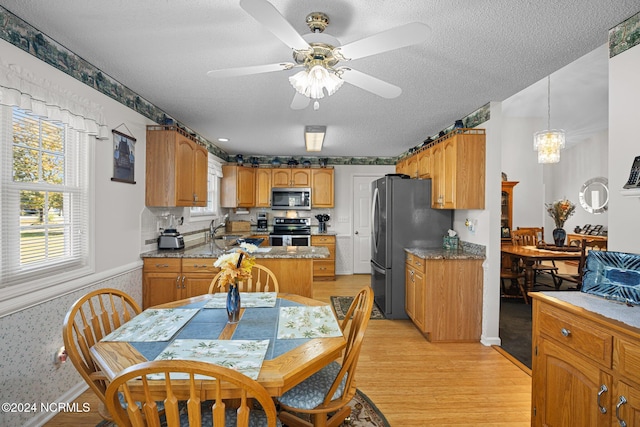 kitchen with ceiling fan, light hardwood / wood-style floors, pendant lighting, a textured ceiling, and appliances with stainless steel finishes