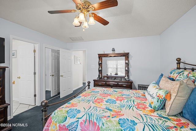 tiled bedroom featuring ceiling fan, a closet, and a textured ceiling