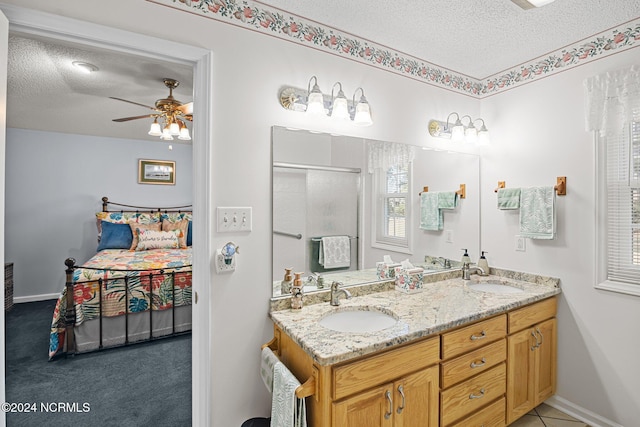 bathroom with ceiling fan, a shower with door, a textured ceiling, and vanity